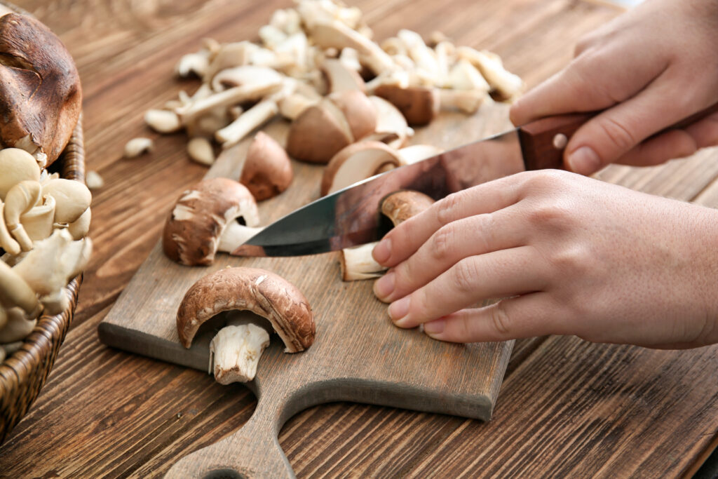 Women cutting mushrooms on a chopping board. 