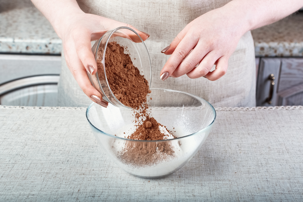 flours and cocoa powder been poured into a glass bowl.