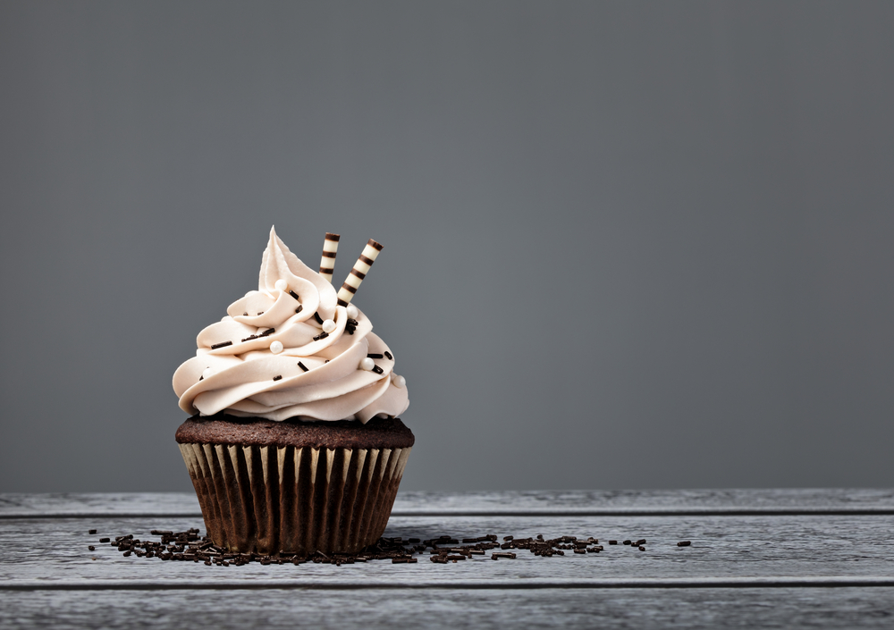 Chocolate cupcake with buttercream icing over a grey background