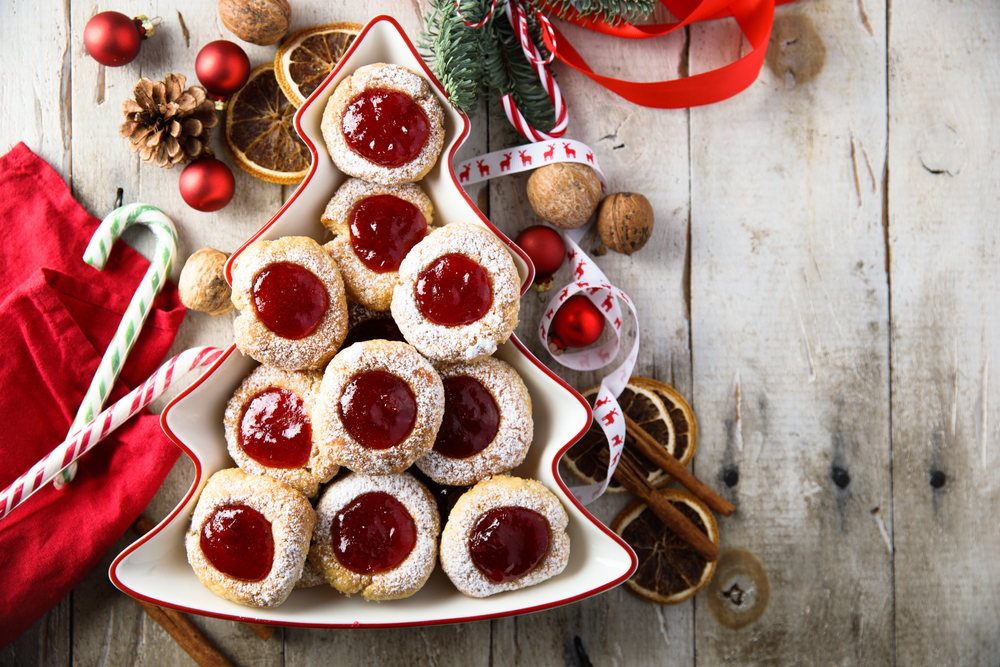 Linzer cookies in a christmas tress chaped plate with christmas decorations around. 