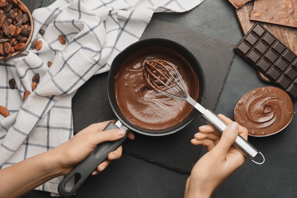 Dairy-free chocolate layer in pan being with a whisk with chocolate near.  