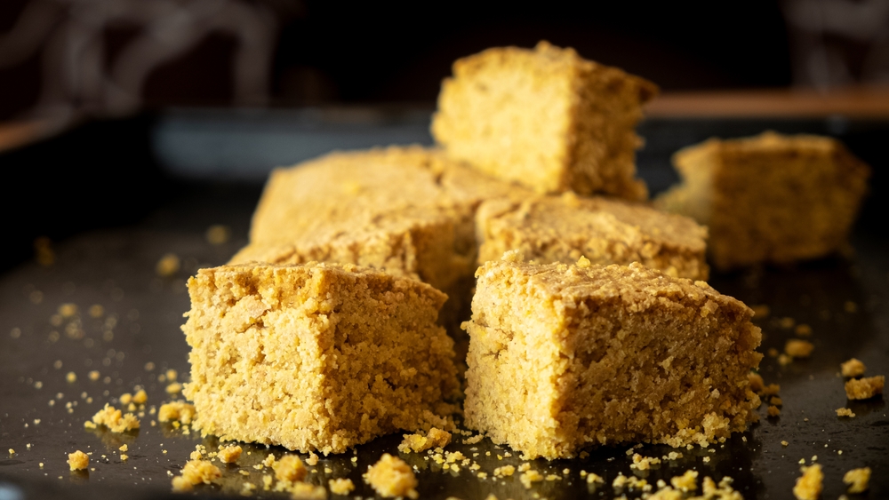 Delicious vegan cornbread. Healthy food. on a black plate with crumbs over the plate. 