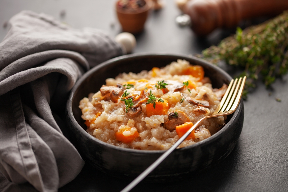 Pumpkin mushrooms risotto with fresh thyme in ceramic bowl. Italian Cuisine.
