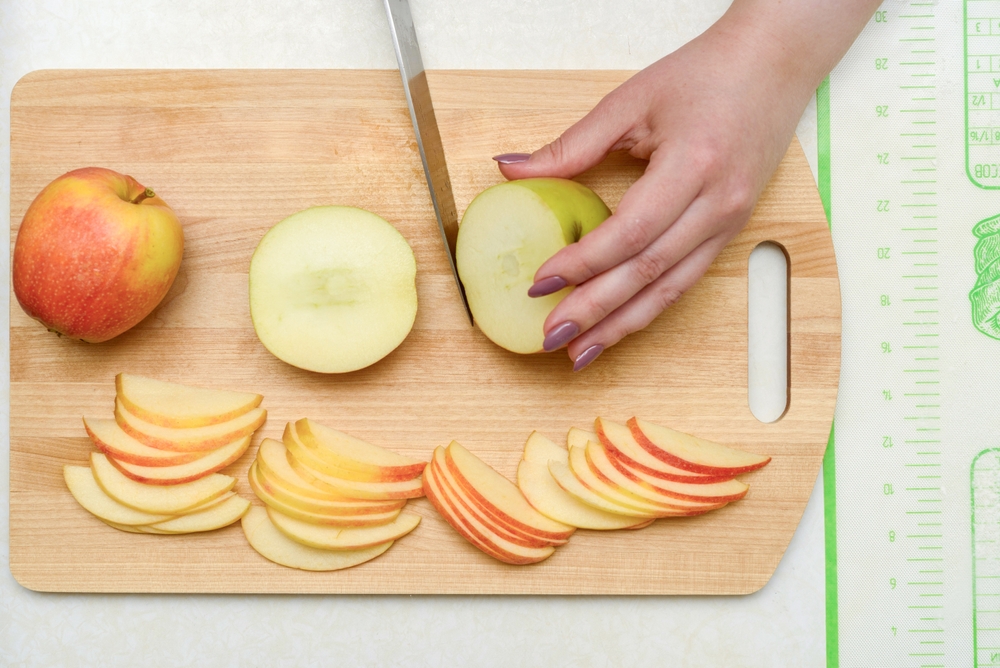 chopping board and someone slicing apples. You can also see a hand and knife. 