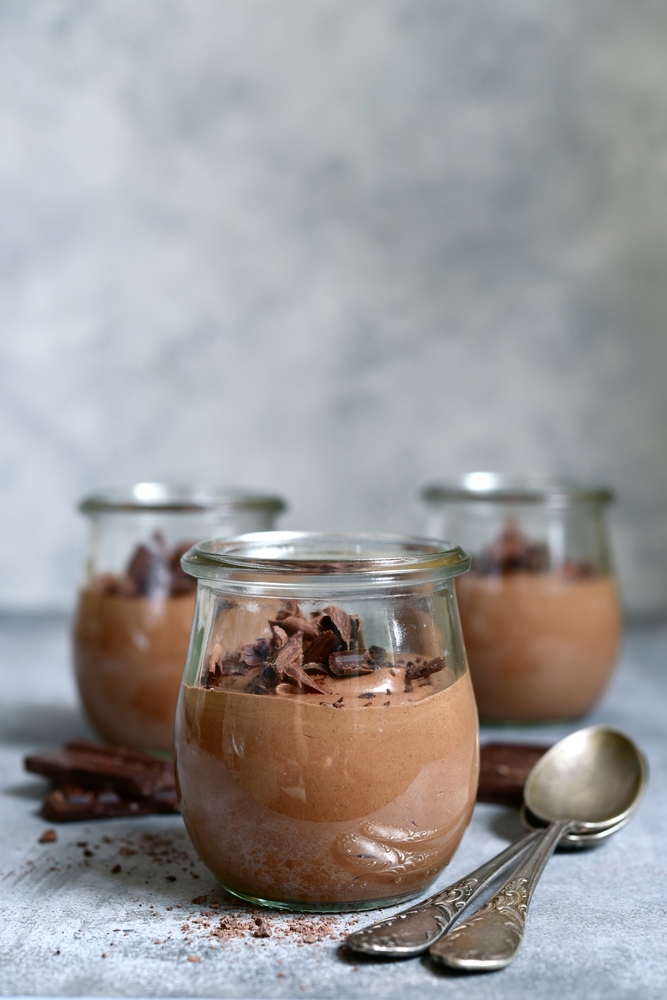 Delicious chocolate mousse in a vintage glasse jar on a light grey slate, stone or concrete background.