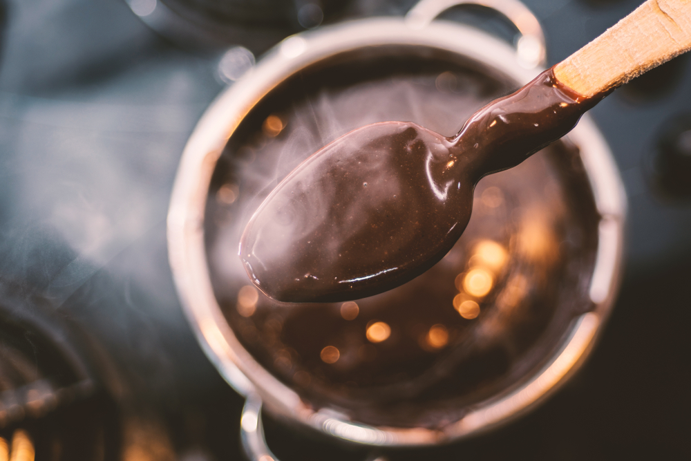 Chocolate pudding in a pan with a wooden spoon on the cooker