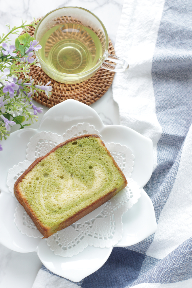 A piece of marble matcha cakes with some matcha tea on a table with flowers.  