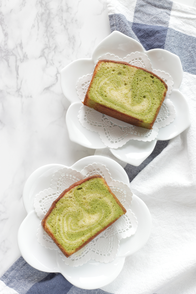 Pieces of green tea marble cake on plates on a marble top. 
