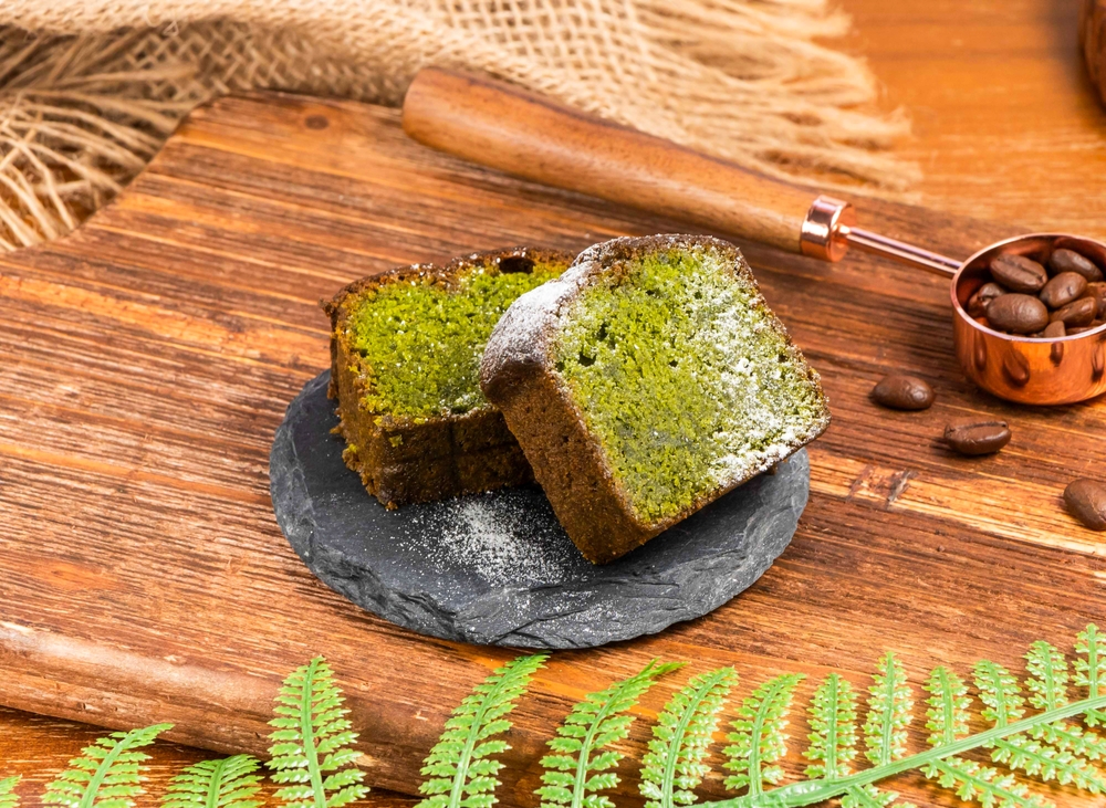 Two pieces of Matcha cake on a slate plate on a brown background. 