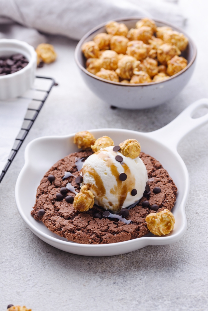 small cookie with chocolate chips, ice cream and popcorn on top. 