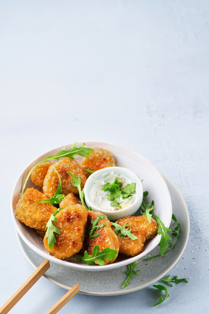 Vegetarian Nuggets with Vegan Dipping Sauce and rocket leaves on a light background. 