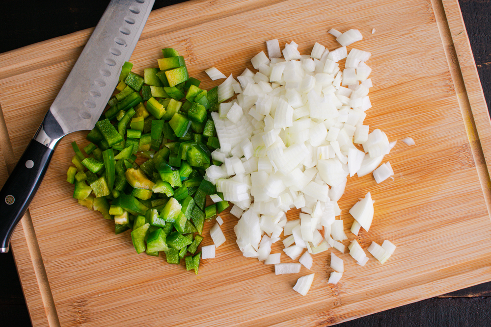 Chopped Green Bell Pepper and Onion on a Bamboo Cutting Board: Overhead view of diced vegetables on a wooden chopping board