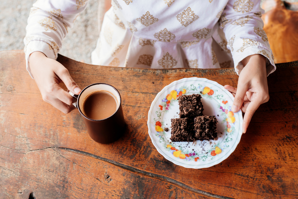 women eating Chocolate and pumpkin brownie slices  at a table with a cup of tea