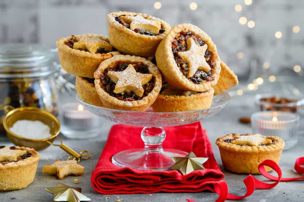 Christmas fruit mince pies on a glass stand. British pastry pies stuffed with raisins, nuts, apples. Selective focus