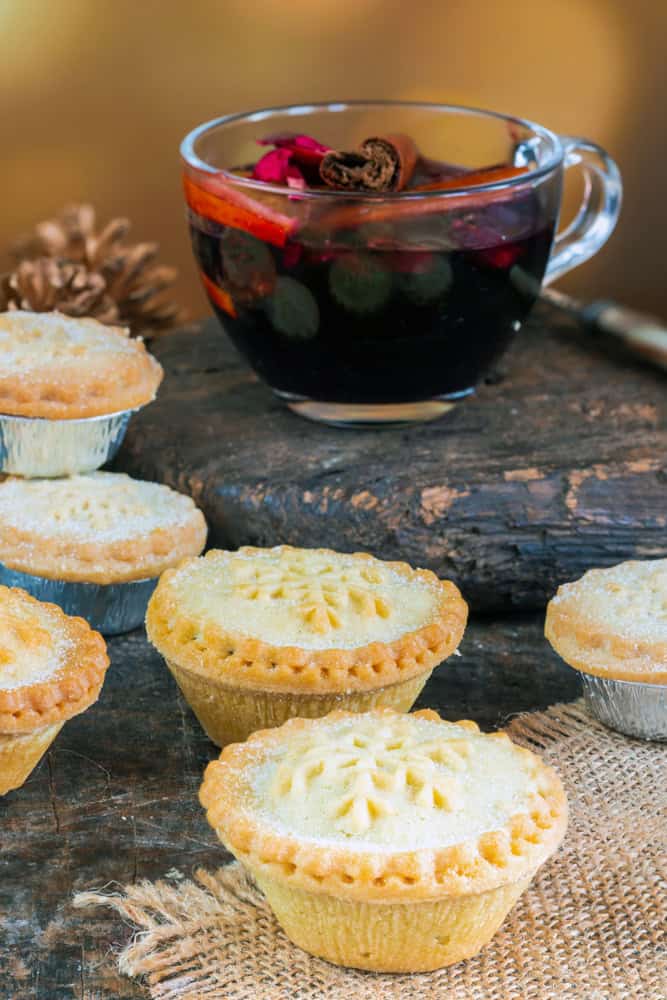 Mince pies on table with a cup of mulled wine.