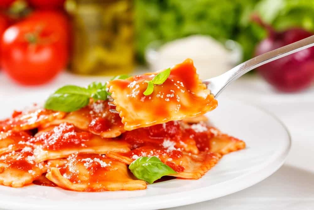 Ravioli pasta meal from Italy eat for lunch dish with fork and tomato sauce on a plate